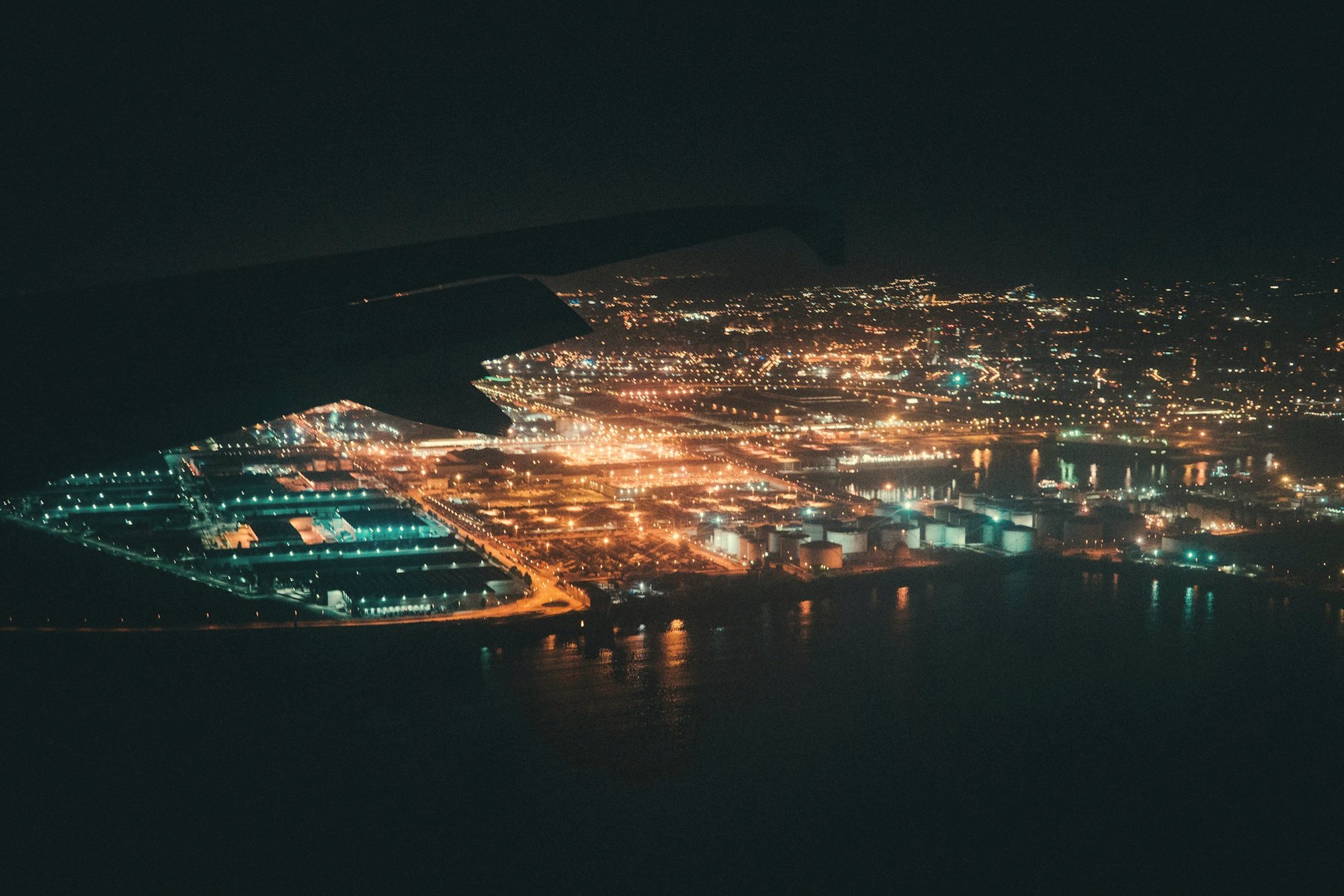 A coastal city's lights at night, seen from the air