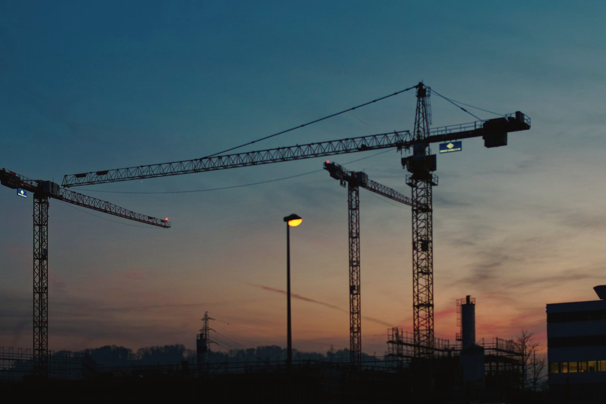 Tower cranes silhouetted against the evening sky