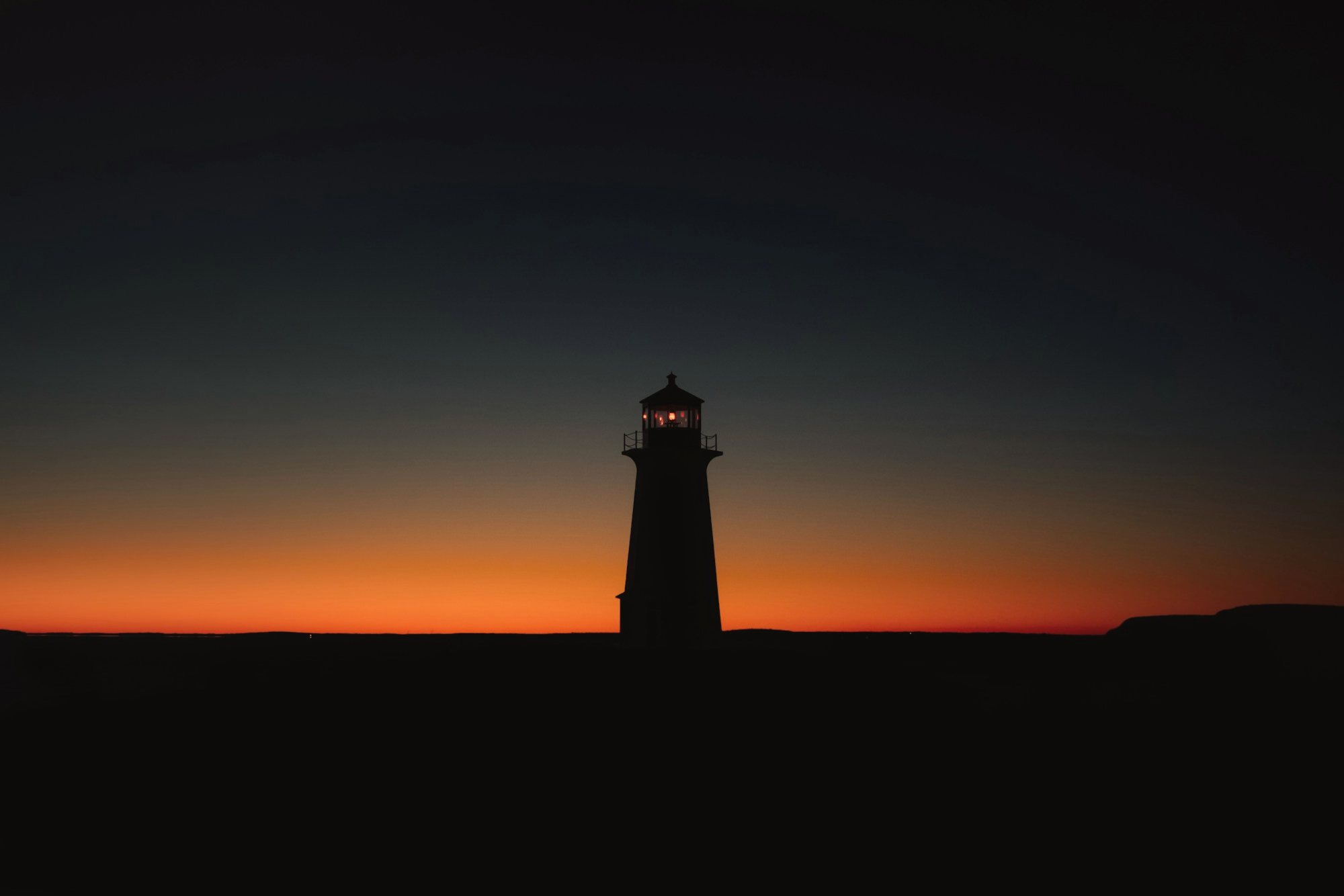 A lighthouse silhouetted at dusk
